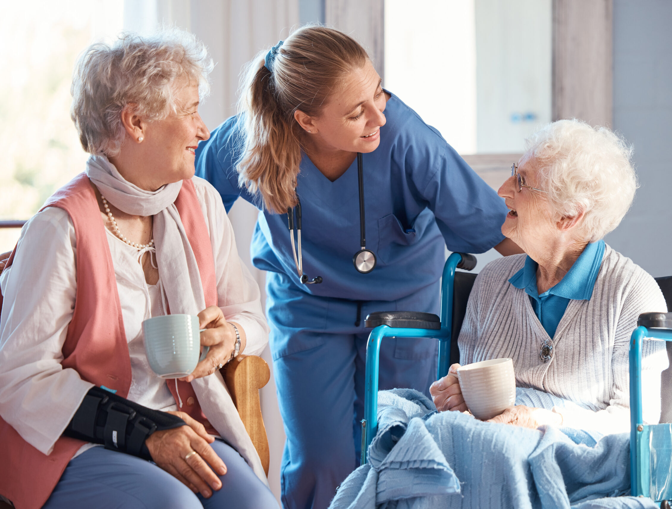 Nursing home, care and nurse with senior women doing healthcare checkup, examination or consultation. Medical, conversation and elderly woman in wheelchair consulting a doctor at retirement facility.
